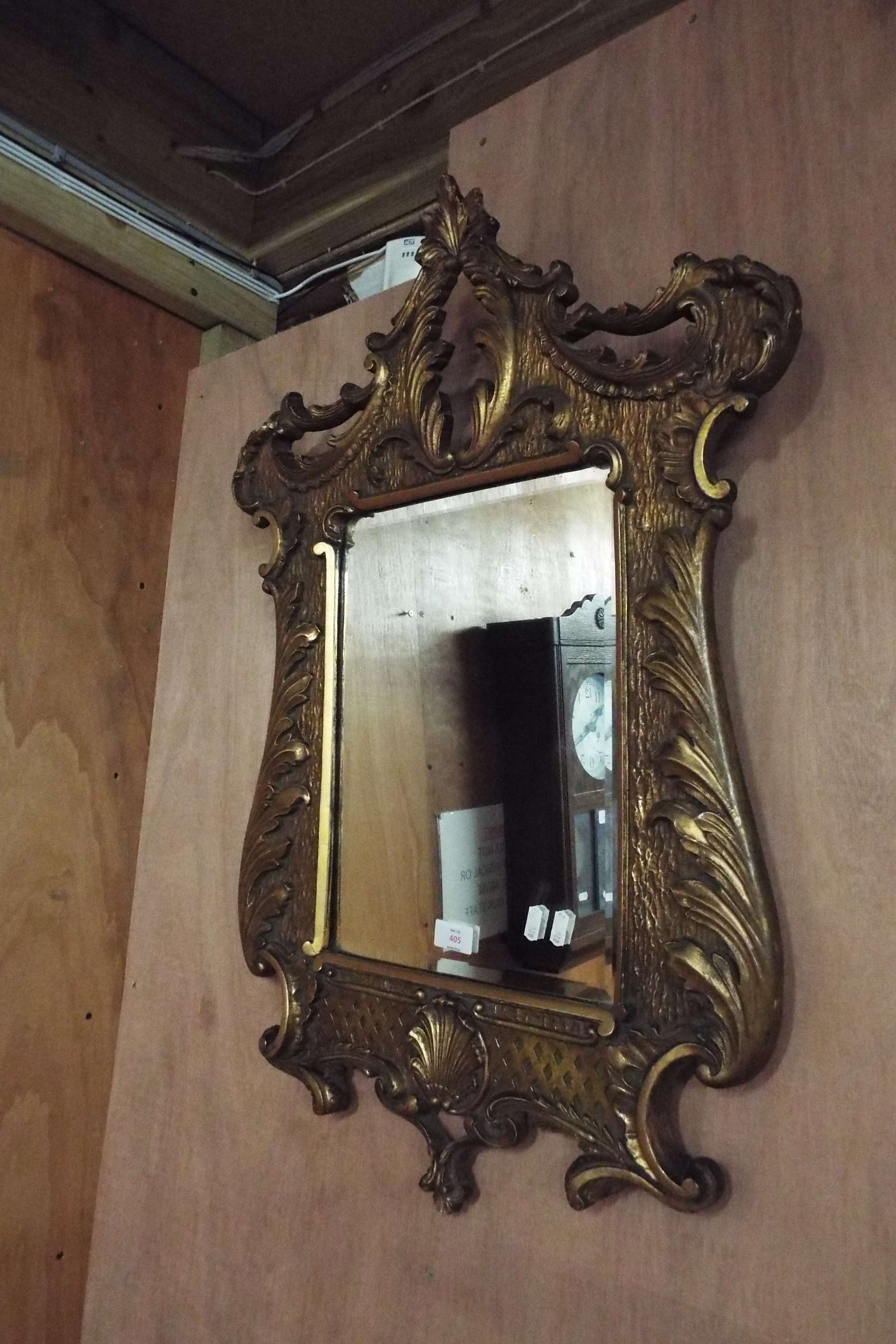 An early 20thC cartouche shaped gilt framed mirror with acanthus leaf border and bevel edge plate