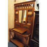 A mid-20thC oak hall stand with central bevel plate mirror over shell and floral scrolled panels