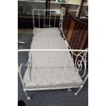 A Victorian wrought iron French day bed with scrolling supports and central cast iron floral panel