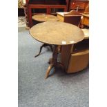 A Georgian oak tilt top side table with bird cage action raised on a baluster support and three out