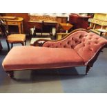 A Victorian mahogany framed arched back chaise lounge having salmon pink button-back upholstery