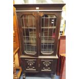 An early 20thC dark oak bookcase cabinet the moulded cornice above a pair of lead lit glazed doors