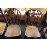 A pair of elm wheel and spindle back side chairs with solid seats and raised on turned supports and