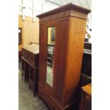 An oak arts and crafts wardrobe having central bevelled mirror door with drawer under