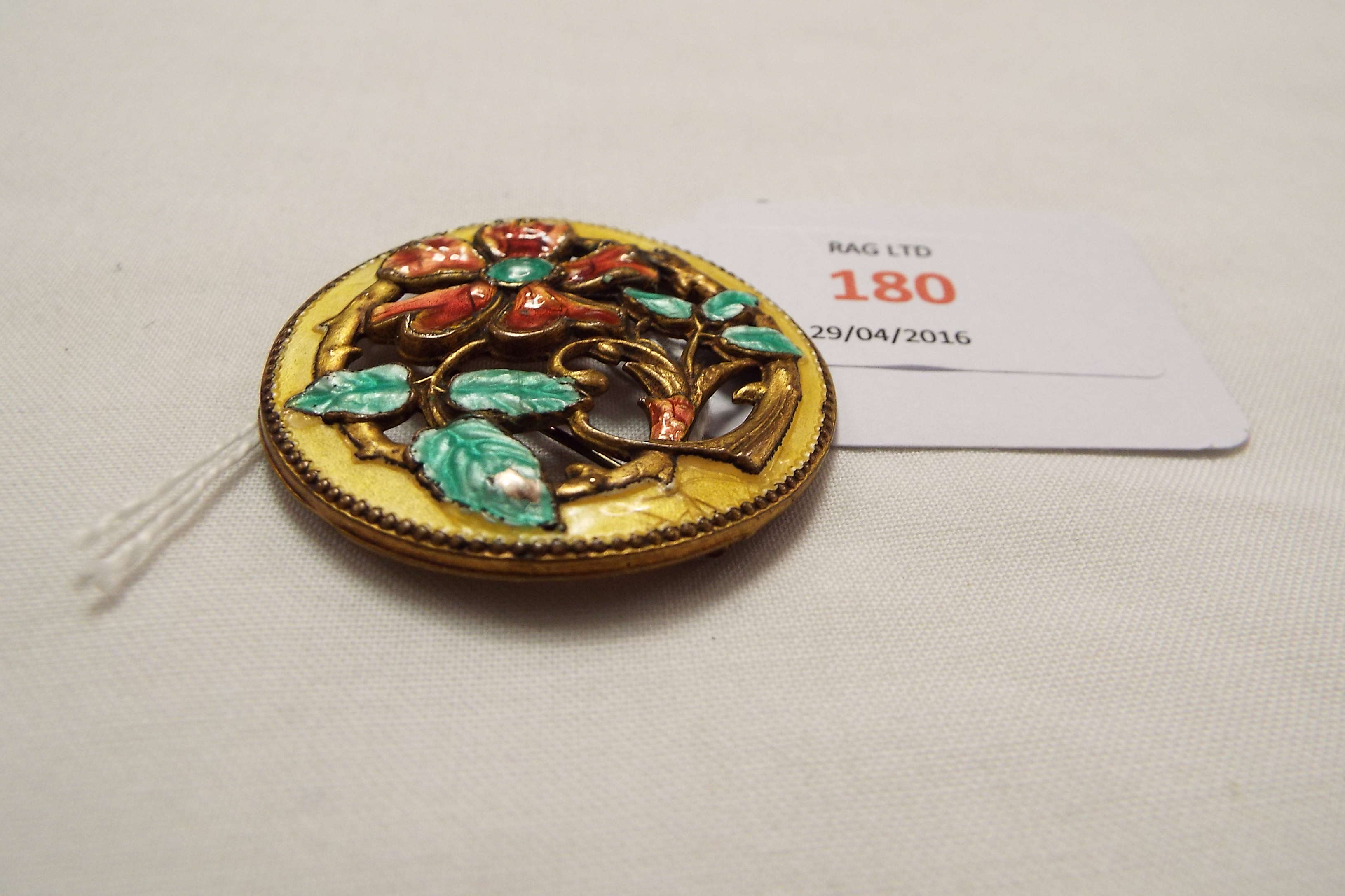 A gilt metal Art Nouveau brooch with enamelled floral design