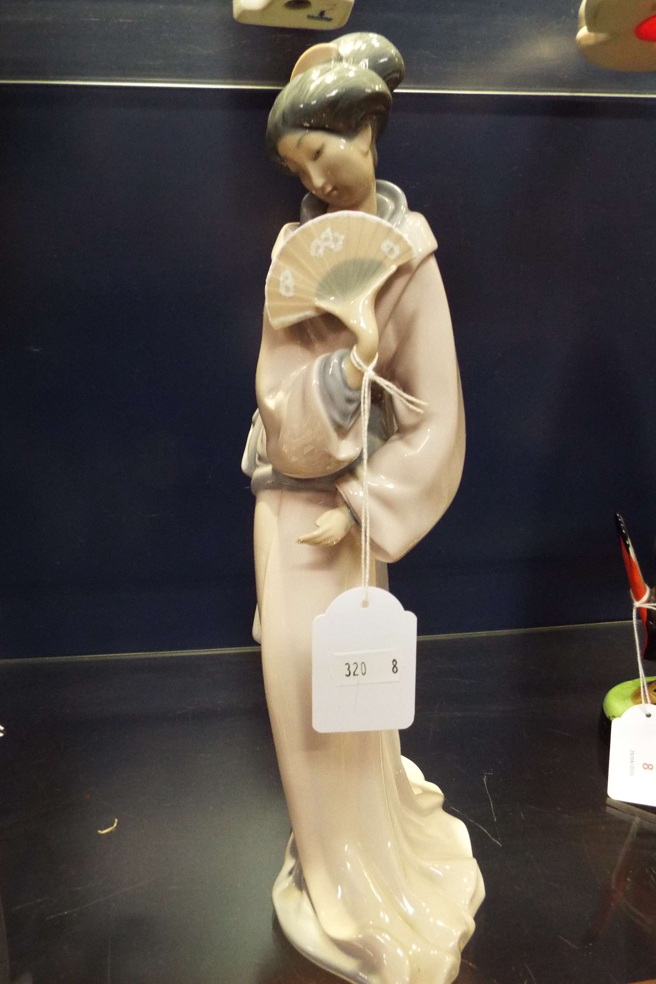 A Nao figurine of a geisha girl with a fan