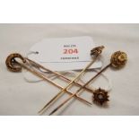 Four gold stick pins to include Etruscan revival design, horseshoe,