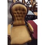 A Victorian mahogany spoon and button back nursing chair in gold upholstery in need of restoration