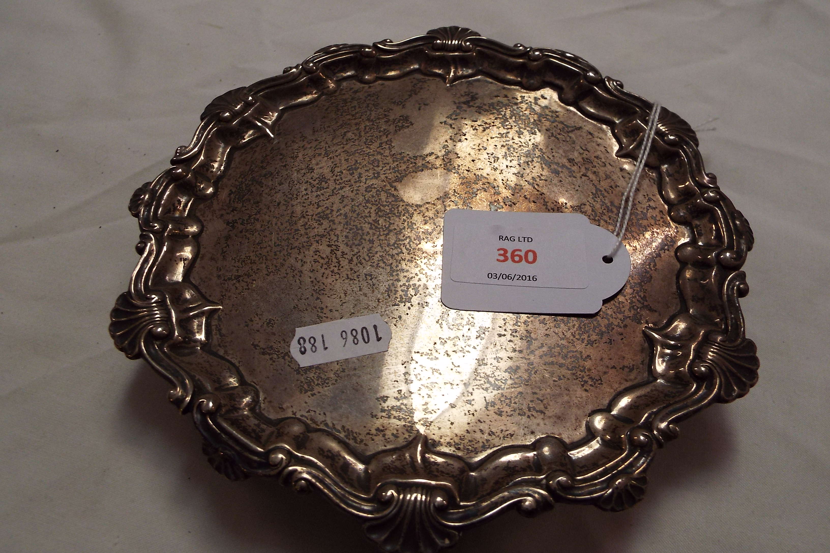 A Chester 1916 silver salver having scroll and shell scalloped rim resting on three ball feet
