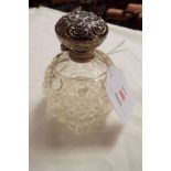 A Birmingham 1910 silver topped perfume bottle having embossed scroll decoration with hob-nail cut