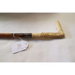 An ivory carved handled cane with floral and swag decoration and engraved metal collar