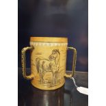 A cream ground Royal Doulton Lambeth three-handled tyg with incised horse and dog decoration by