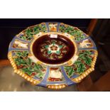 A Mintons Majolica charger having panel decoration of holly and berries and putti,