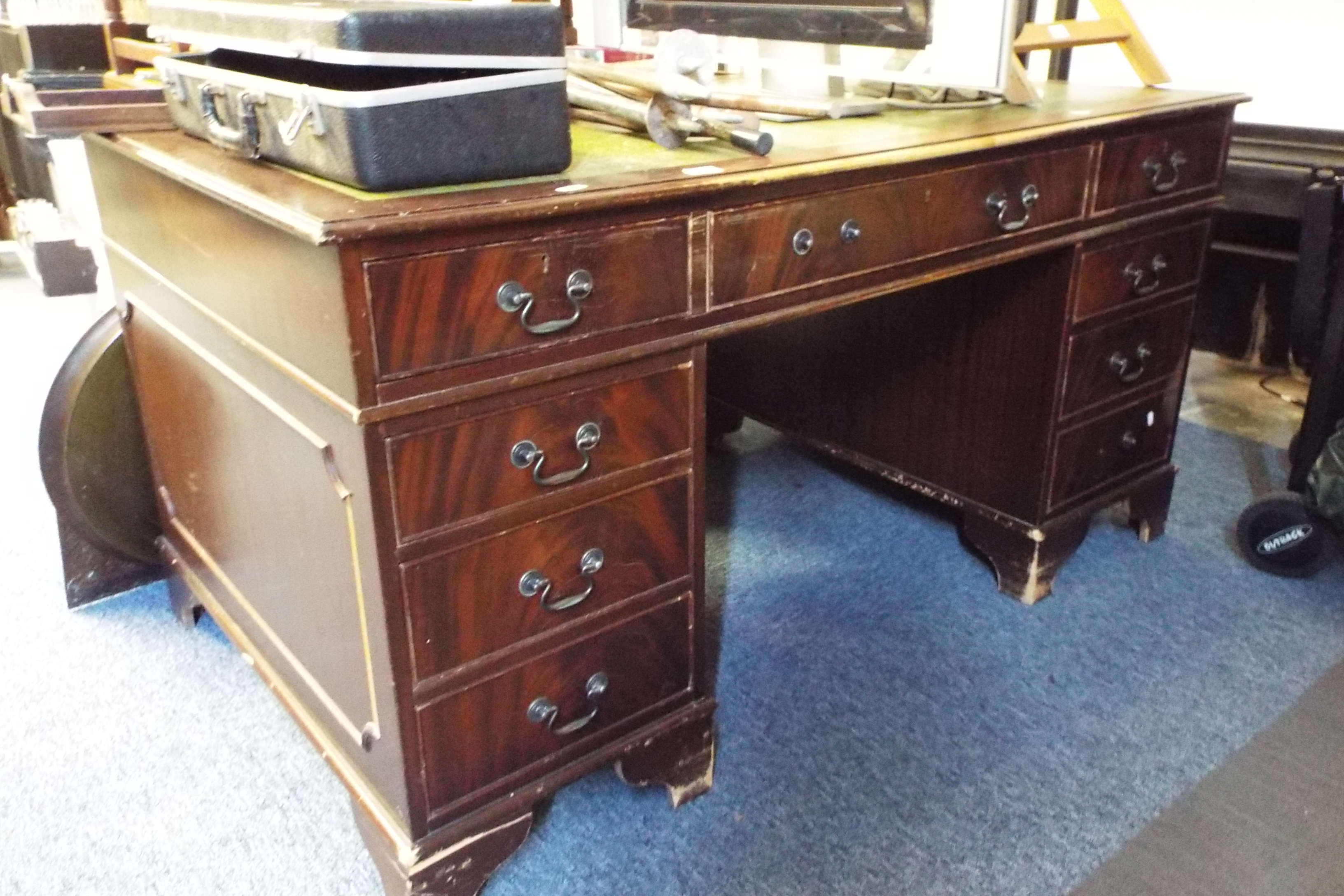 A reproduction mahogany pedestal desk having central drawer flanked by eight short drawers