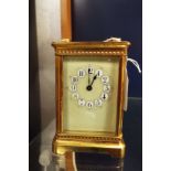 A brass and glass carriage clock having enamelled dial,