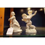 A German porcelain figure of playing putti and a Dresden figure of a putti seated on a crest