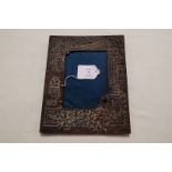 A metal photograph frame with ornate embossed architectural,