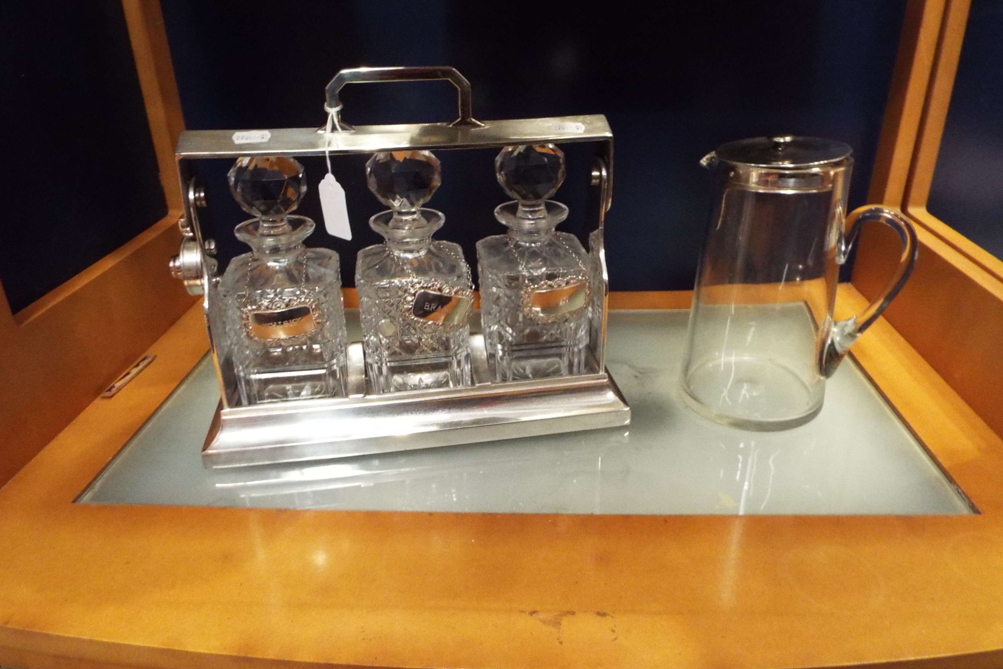 A silver plated tantalus complete with decanters and plated bottle labels for 'Whiskey', 'Brandy',