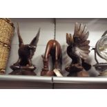 A pair of carved wooden eagles and another