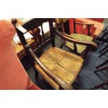 An Edwardian elm open armchair with rose carved spindle back over similar carved scrolling arms and