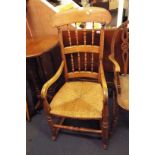 An Edwardian elm spindle back rocking chair with rush upholstered seat and turned supports