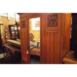 An Edwardian satin wood wardrobe having central bevelled mirror door flanked by carved panels with