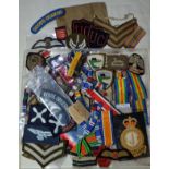 Large selection of various military cloth badges including rank insignia, medal ribbons,