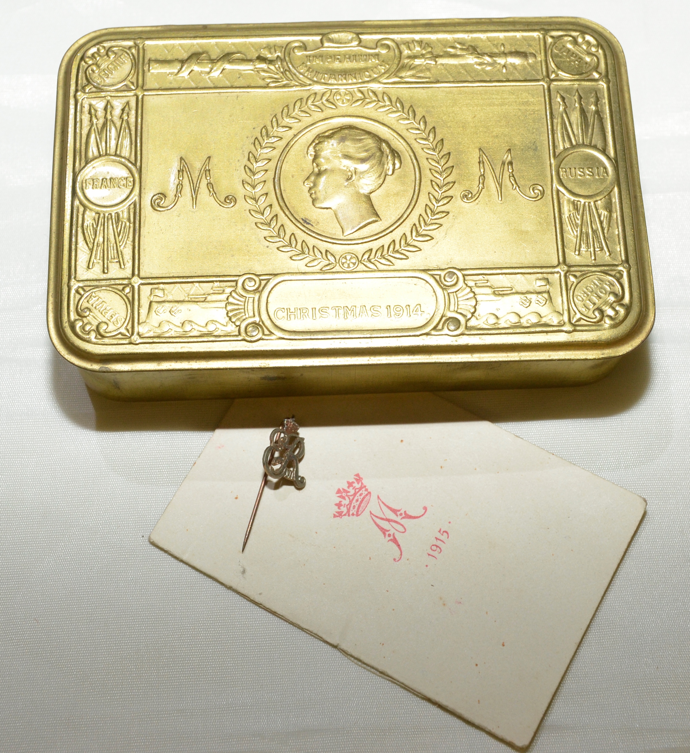 1914 chocolate tin with original Queen Mary presentation card and a ER IIV lapel badge