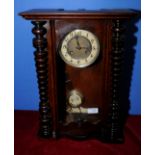 Striking wall clock in stained beech case with glazed door and turned column supports,