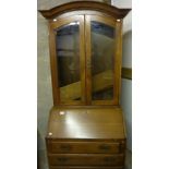 Oak bureau bookcase with arched top and two glazed doors above fall front and four drawers