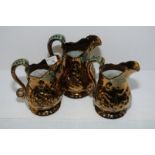 Set of three graduating copper lustre jugs with green painted detail and moulded detail