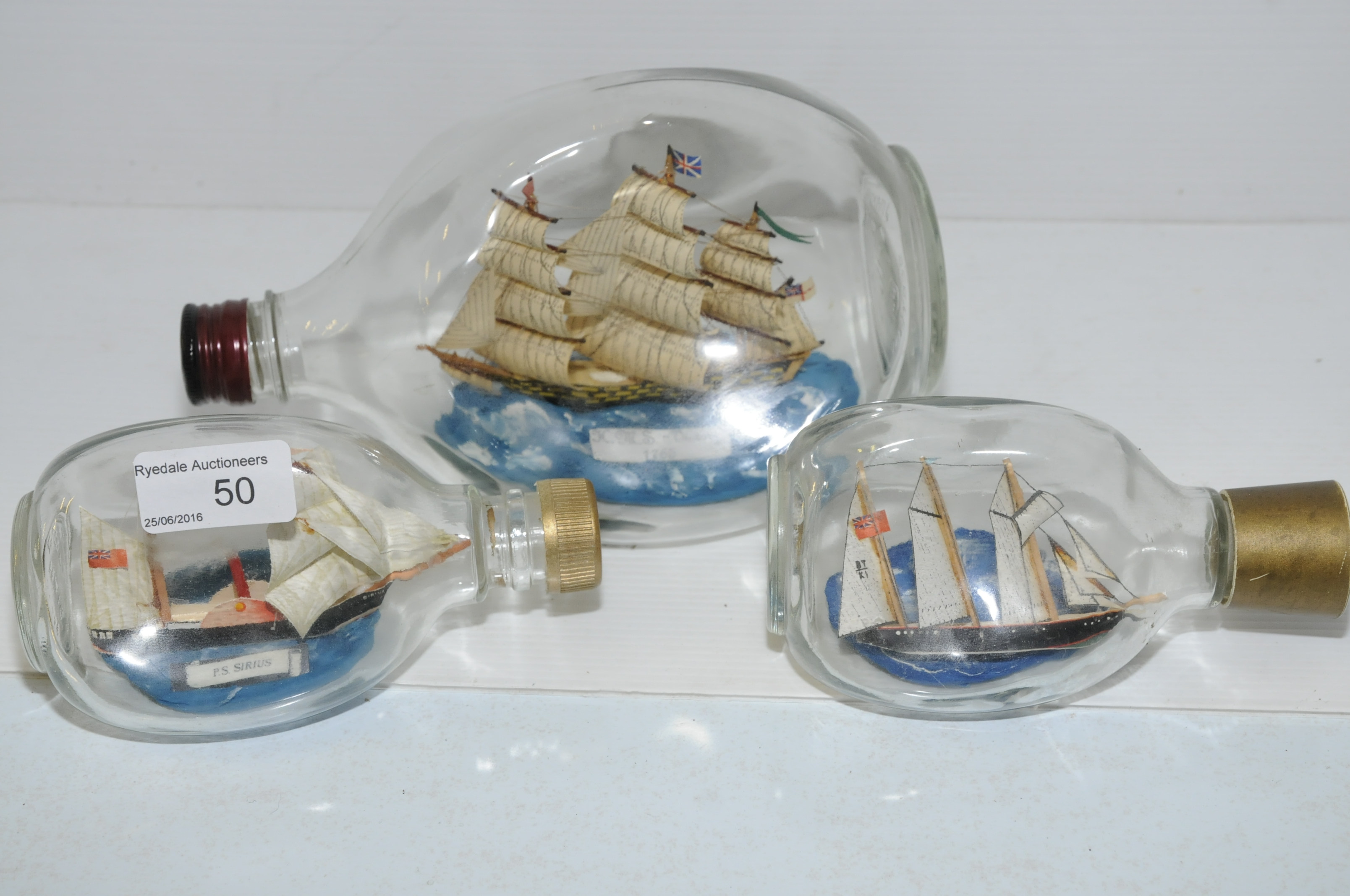 Three graduating ships in bottles