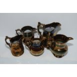 Two copper lustre jugs with blue painted decoration and moulded detail and three others