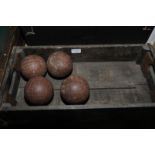 Four antique skittle balls in wooden crate