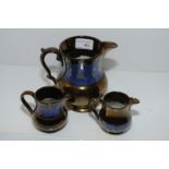 Three copper lustre jugs with blue borders