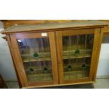 Art Nouveau style oak wall cabinet enclosed by a pair of led glazed doors