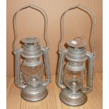 Two steel Anchor Brand tilly lamps