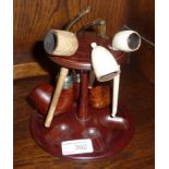 Turned wood pipe stand and a selection of various pipes including clay and turned wood with silver