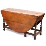 Property of a lady - a large 18th century oak oval topped gate-leg dining table with end drawer on