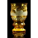 A 19th century Bohemian amber glass beaker with etched decoration depicting a stag in landscape,