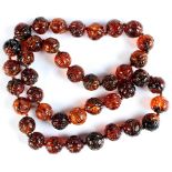 A good Chinese carved amber bead necklace, the forty large round amber beads individually knotted,