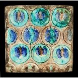 An Iznik style pottery tile, with incised blue & green glazed flowerheads, approximately 7.6ins. (