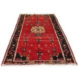 A Kordi woollen hand-made rug with red ground, 116 by 66ins. (295 by 170cms.) (see illustration).