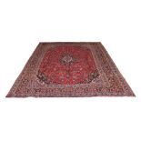 A Meshed woollen hand-made carpet with red ground, 153 by 110ins. (390 by 280cms.) (see