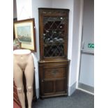 A XX Century Jaycee Oak Double Corner Cupboard, with a carved frieze, leaded glazed door over a