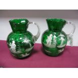 A Pair of Late Victorian Green Glass Jugs, each white enamelled in the Mary Gregory manner with