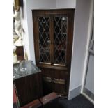 An Oak Freestanding Corner Cabinet, with lead glazed upper doors, knulled pediment and panelled
