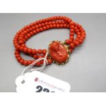 A Three Row Coral Bracelet, of uniform design, to oval carved coral cameo style clasp, depicting