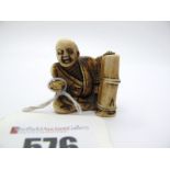 Japanese Meiji Period Ivory Netsuke, carved as a seated elder by bamboo drum, 3.3cm high.