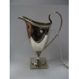 A Hallmarked Silver Helmet Shape Cream Jug, with reeded edge and high loop handle, on square base.